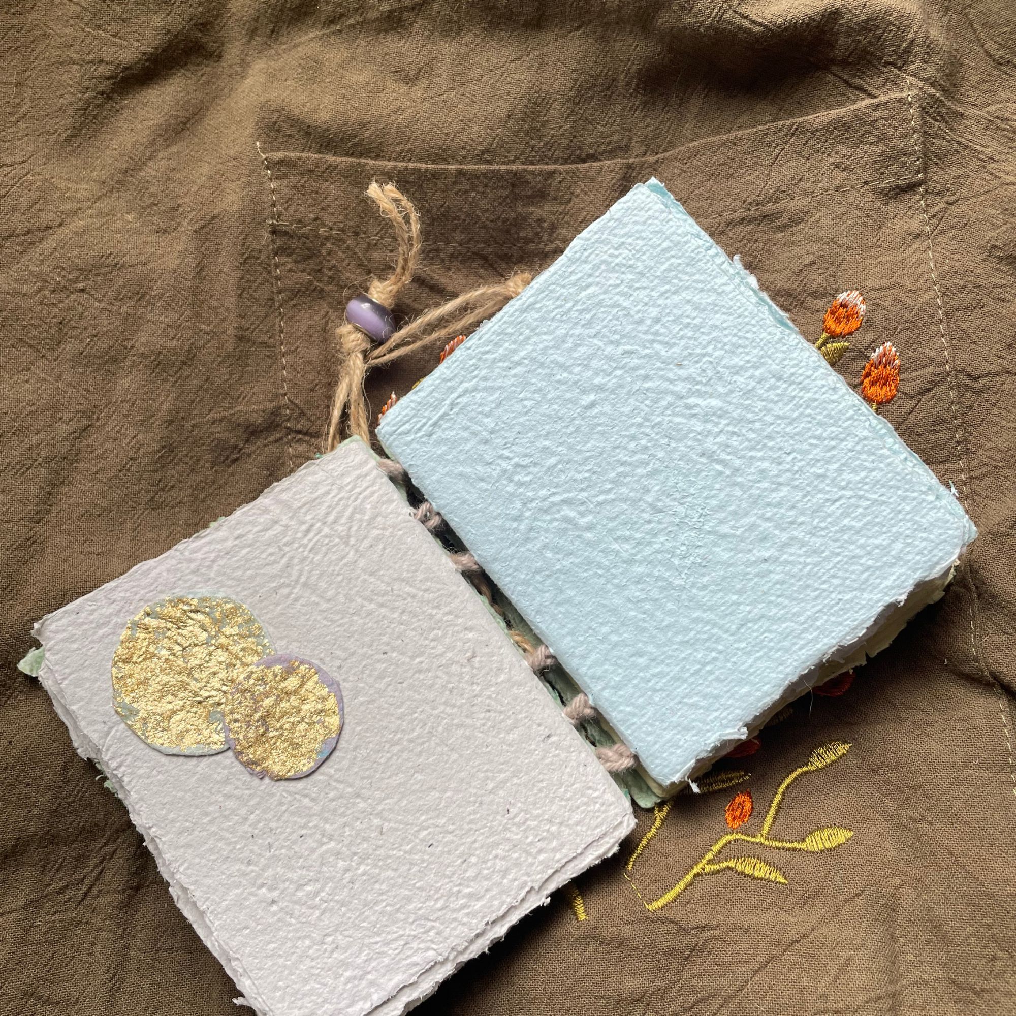 Meadow Stitch pocket journal opened to show handmade paper pages and Coptic binding