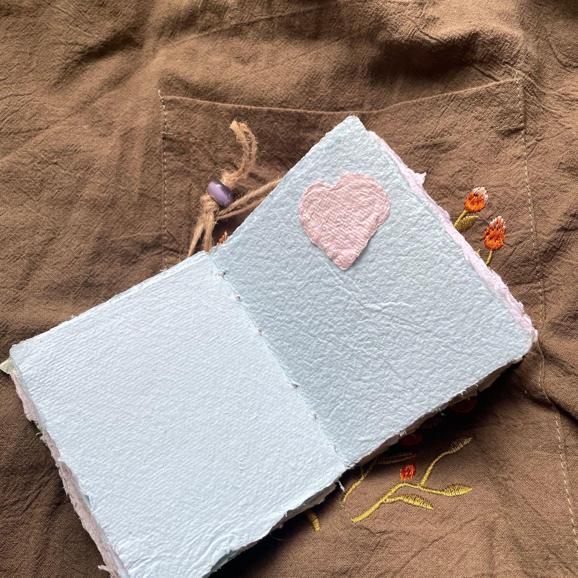 Meadow Stitch pocket journal opened to show handmade paper pages and Coptic binding