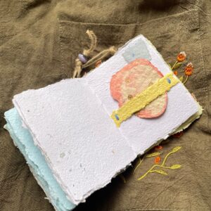 Meadow Stitch pocket journal opened to show handmade paper pages and Coptic binding