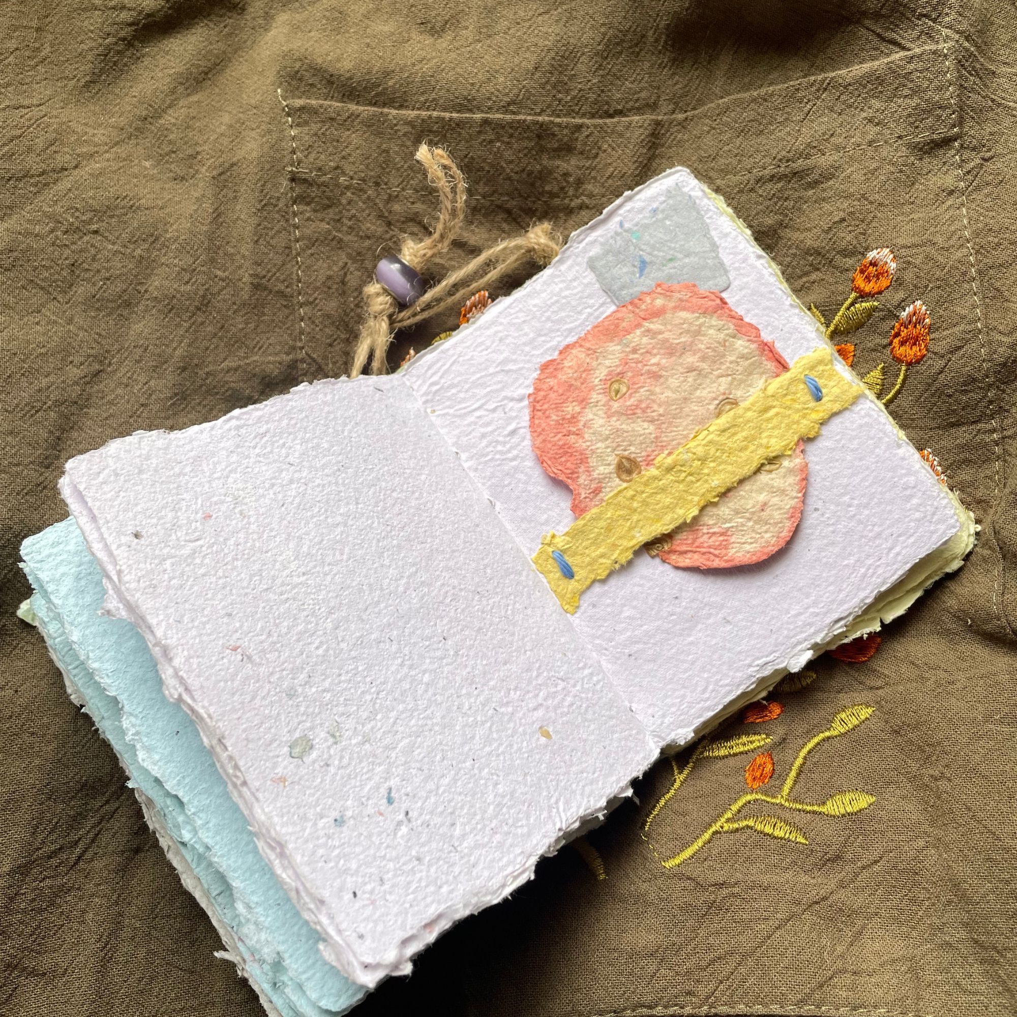 Meadow Stitch pocket journal opened to show handmade paper pages and Coptic binding