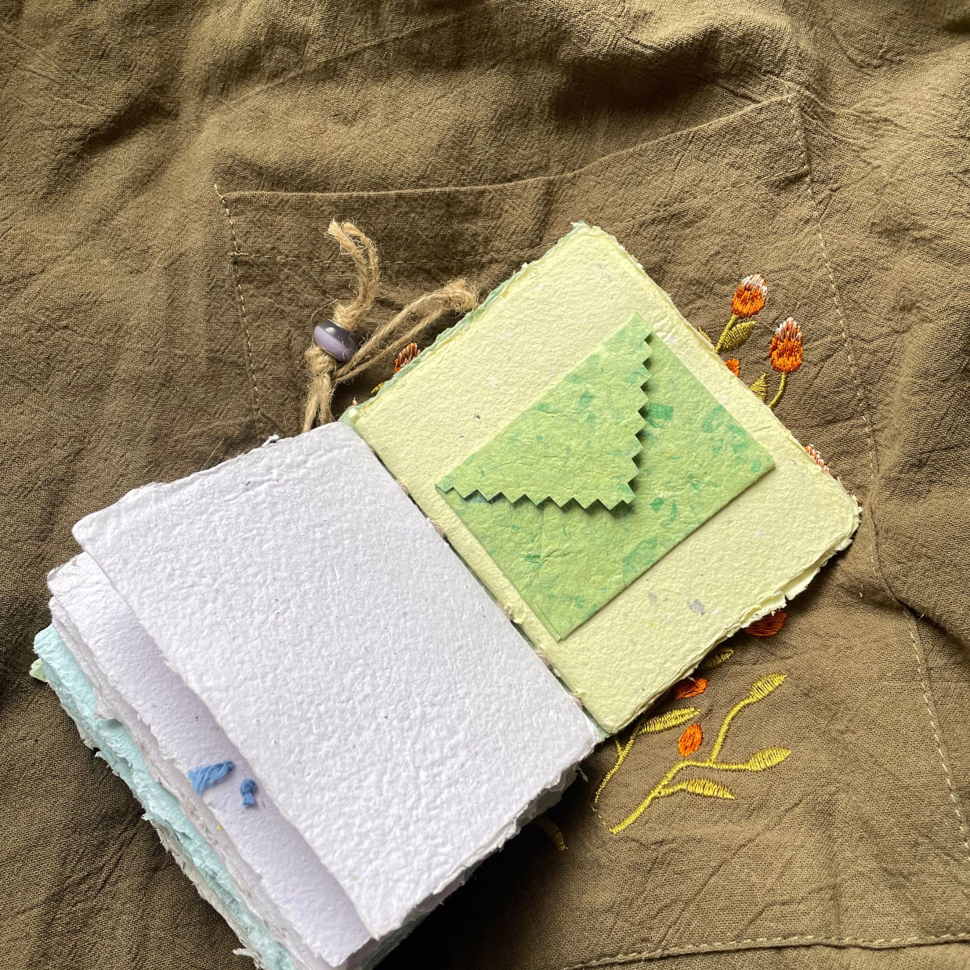 Meadow Stitch pocket journal opened to show handmade paper pages and Coptic binding